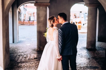 Nevěsta a ženich se líbají pod kamenitými oblouky.